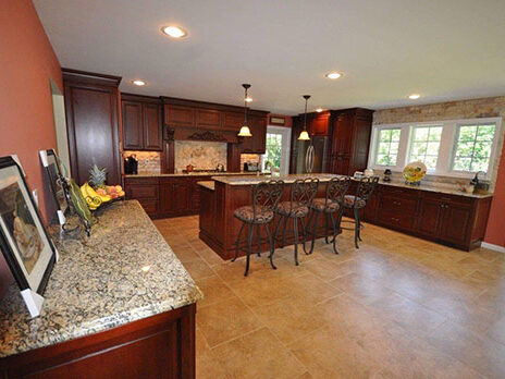 Indoor-wood-kitchen-finished-with-cherry-colored-stain-granite-counter-tops-and-porcelain-floors-Commack-NY