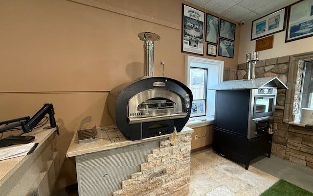 RossoFuoco Clessidra oven with a fire, prepared for direct and indirect cooking outdoors.