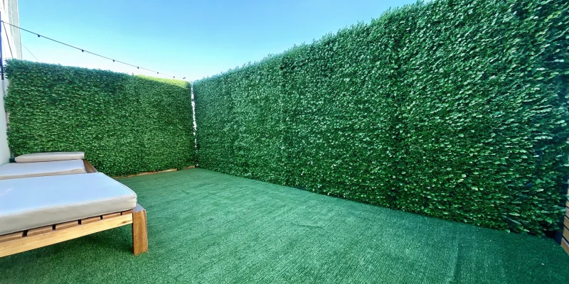 An artificial ivy wall creates a lush, green privacy fence for an outdoor space.