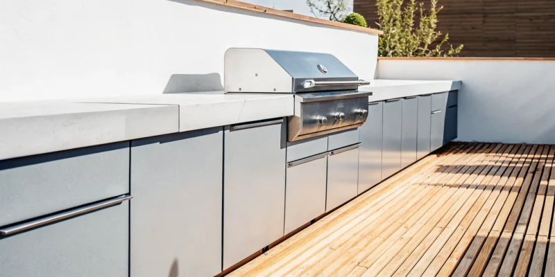 A Brown Jordan outdoor kitchen with durable stainless steel cabinets and a grill on a modern deck.