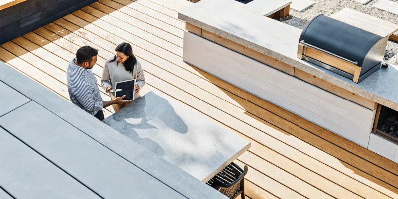 An outdoor kitchen contractor in Long Island, NY, reviewing design plans on a modern patio.