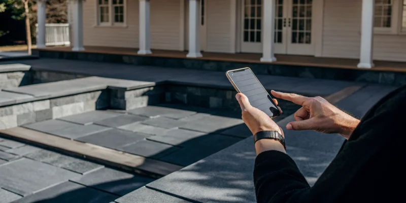 Person searching for an expert outdoor living contractor in Long Island, NY on a phone.