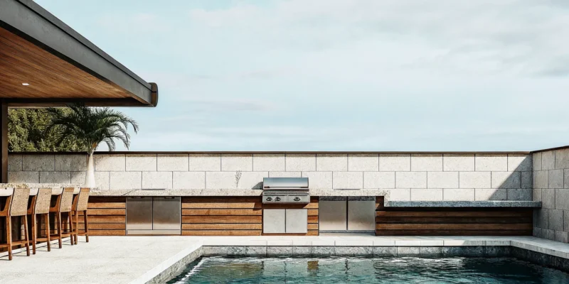 Modern outdoor kitchen design with a large stone island, built-in grill, and poolside seating.