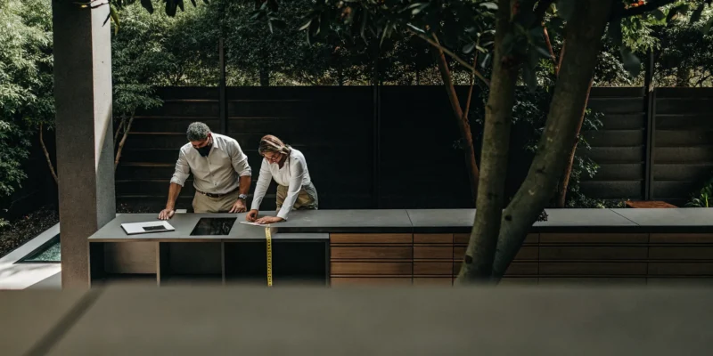A contractor and client planning a custom outdoor kitchen construction project.