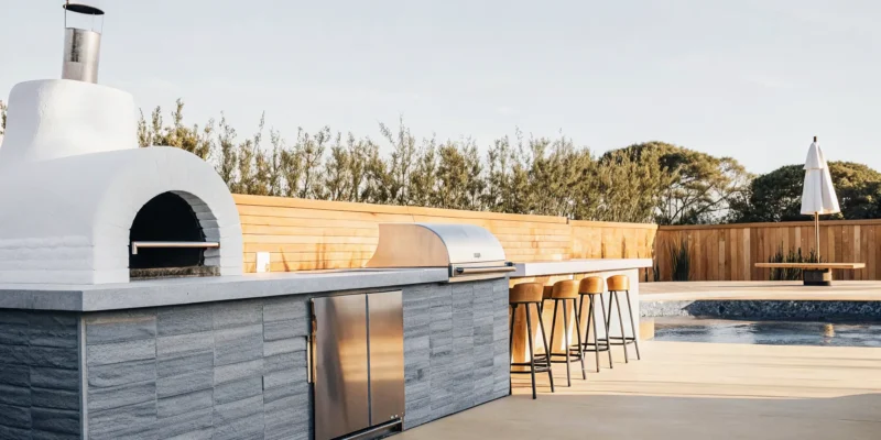 Modern outdoor kitchen with a grill and bar seating designed by a Long Island NY contractor.