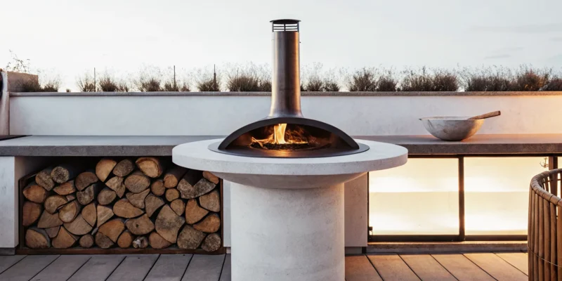 Clementi Colorado wood-fired cooktop & firepit with a central fire and wood storage base.