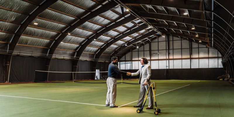 Sports game court contractors shaking hands on a finished tennis court on Long Island NY.