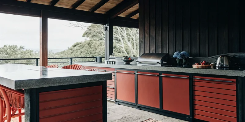 Serene outdoor kitchen cabinets with red panels at a Long Island dealer showroom.