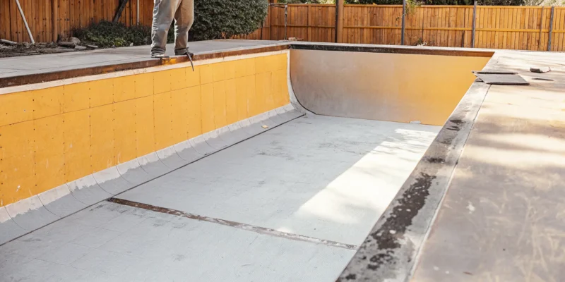 Empty inground swimming pool with concrete walls being prepared for a new vinyl liner installation