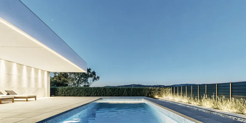 Luxury outdoor kitchen designs with a modern patio, pool, and ambient lighting at sunset.