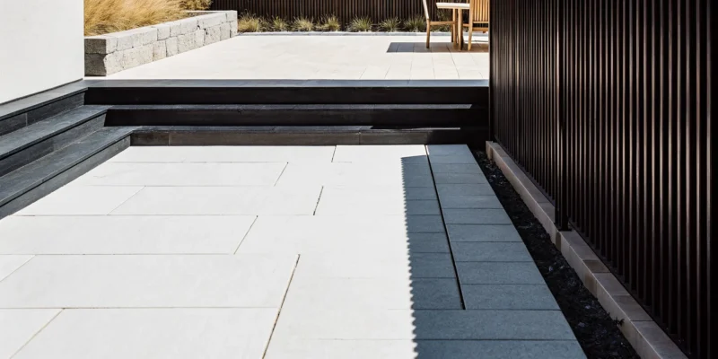 Modern bluestone patio design with clean geometric pavers and contrasting stone borders.