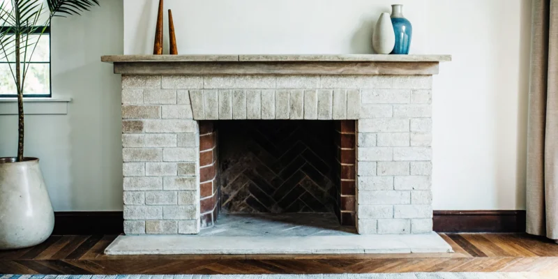 Antique brick fireplace idea with a simple mantel and light stone surround.
