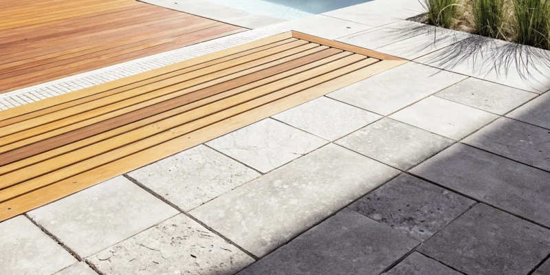 The best travertine for a pool deck, featuring light-colored pavers around a modern swimming pool.