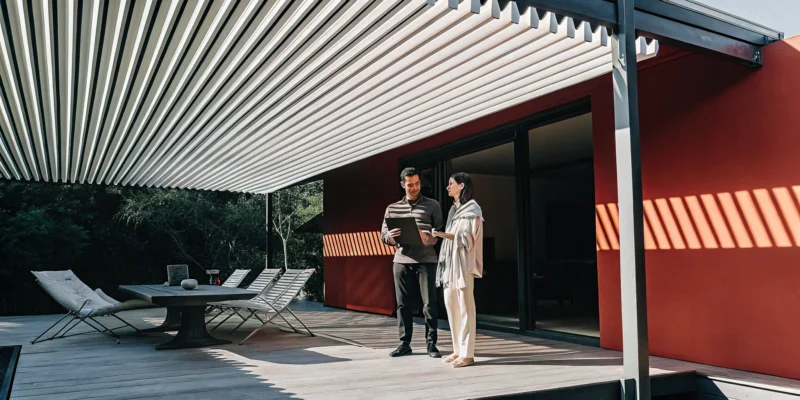 A shade structure contractor discusses plans with a client on a Long Island patio.