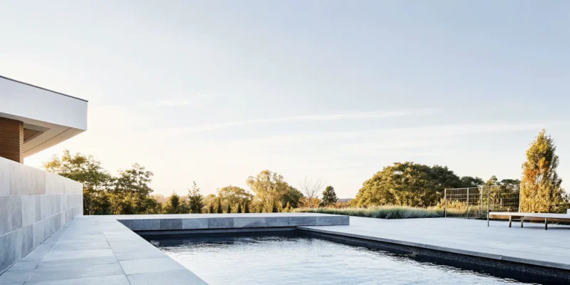 Natural stone waterfall and koi pond surrounded by bluestone patio and landscape in a Long Island backyard