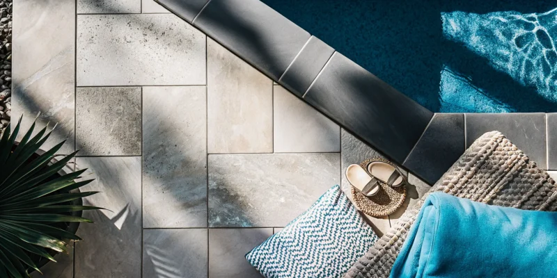 A beautiful natural stone patio by a pool, a major factor in overall project cost.