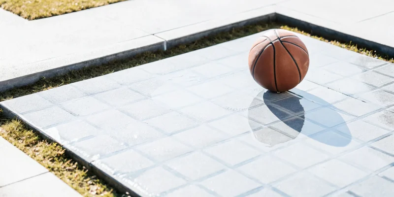 Basketball court tiles placed over grass, sinking unevenly into the lawn.